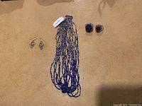 Full view of Himalayan jewelry lot showing blue and white multi-strand beaded necklace, two pairs of earrings on left, and two rings with large stones on right
