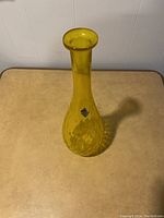 Full view of the tall yellow Neapolitan glass vase showing its shape and color.