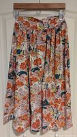 Full view of 1950s cotton skirt with orange and green artistic motif, showing its full length and gathered waistline.