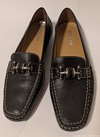 Pair of black leather Geox Respira loafers with silver buckle detail and white contrast stitching shown from top angle.
