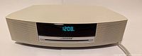 Front view of cream-colored Bose Wave Music System unit displaying 12:08 on LED screen