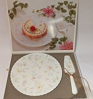 View of cake plate and server in original box with image of cake on lid interior.