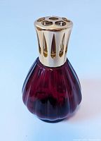 Front view of ruby red glass Lampe Berger with gold-finish top in pristine condition.