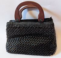Front view of black leather woven mesh purse with wooden handles showing texture and handle shape