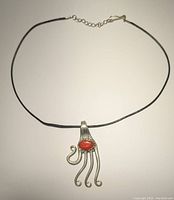 Photo of silver-tone vintage fork pendant necklace with orange oval stone on a fine chain laid flat.