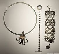 Photo of choker necklace with a central decorative pendant shaped with loops on silver coloured wire band.