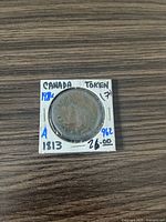 Front side of the 1813 Canada Trade and Navigation Token showing the bust design and handwritten details on holder.