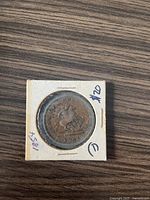 Obverse side of the 1854 Bank of Upper Canada One Penny coin showing Queen Victoria's portrait, mounted in a paper coin holder labeled '1854' and marked with a $20 price.