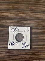 Front view of the 1938 Newfoundland silver 5 cent coin in a protective coin flip holder with handwritten notes indicating 100k mintage and $150 estimated value.