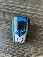 Shot glass showing Batman's face in blue, white, and black on black background