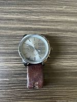 Front view of Diesel watch showing silver-tone dial, chronograph subdials, and worn brown leather strap.