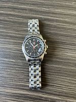 Front view of ESQ chronograph watch showing black dial, stainless steel bracelet, and red seconds hand.