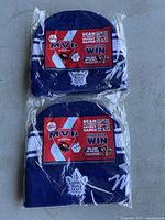 Two packaged knitted blue and white toques with Toronto Maple Leafs and Molson branding, promotional red MVP contest card attached