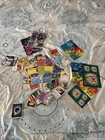 Overview of Pokémon cards spread on a blanket with some large Pokémon stickers to the side.