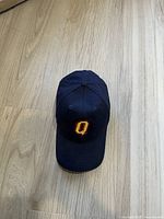 Top-down view of blue baseball cap showing the yellow 'Q' logo embroidered on the front.