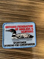 Front of the patch showing embroidered design with loon bird and text 'Ontario Federation of Anglers & Hunters Sportsmen Working for Conservation'.