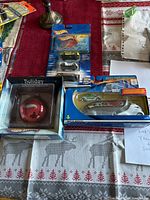 Full view of four items together on table including boxed holiday decoration and three Hot Wheels model cars in original packages.