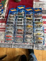 Full lot layout of 33 Hot Wheels cars in opened packages spread out on table