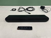 Front view of VMAI Mini 7 sound bar with remote and cables laid out showing included accessories.