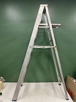 Side view of 6-foot aluminum step ladder showing its A-frame structure and paint stains on the legs and steps.