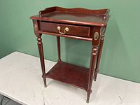 Front view of small cherry red wooden table with drawer and turned legs