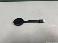 Google Chromecast streaming device, oval shaped, black, with HDMI connector