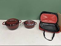 Two KitchenAid ceramic cookware dishes side by side and Anchor Hocking insulated serving dish with carrying case open to show inside