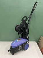 Pressure washer full front-left side view showing body, wheels, hose, and handle.