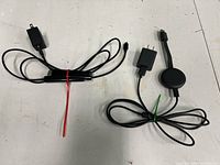 Roku streaming stick with power adapter and cables on the left, Google Chromecast with power adapter and cables on the right, all laid out on a white surface.