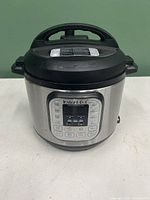 Front view of stainless steel InstantPot electric pressure cooker with digital display and buttons.