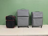 Front view of three suitcases in different sizes posed side by side against green background.