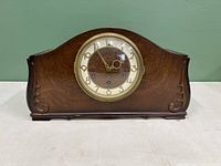 Front view of the vintage Seth Thomas Portsmouth mantel clock showing curved wooden case and clock face with gold numerals and hands under glass.