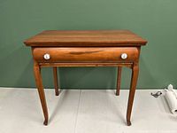 Front view of vintage wooden sideboard showing drawer with two white decorative knobs and curved legs.