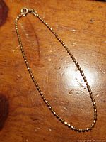 Full view of 7.5 inch faceted bead chain bracelet with spring ring clasp on wooden surface