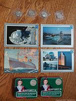 Lot showing 4 colorful Expo 86 themed postcards, 5 collectible coins in protective sleeves, 2 Export A cigarette tins with health warnings.