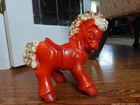 Front left view of red pony ceramic planter showing detailed curled mane and saddle-shaped opening on back.