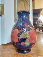 Vintage Moorcroft pottery vase shown from three angles to display fruit design and rim condition.