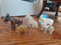 View of five hand sculpted onyx burro figurines arranged on wooden floor, showing front and side angles.