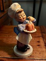 Front view of the vintage Hummel figurine depicting the baker boy holding a plate with a dessert, highlighting facial expression and details.