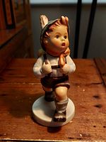 Front view of the vintage Hummel Goebel figurine "Schoolboy" showing the boy walking forward with mouth open, wearing traditional clothes and carrying a backpack.