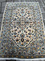 Full view of the rectangular handmade Persian wool rug with floral design and central medallion, showing overall condition and color scheme.