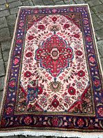 Full view of the rectangular Tabriz Persian rug showing the ivory background with a central red and blue medallion and the surrounding floral patterns with dark blue border.