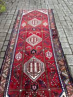 Full-length view of the red field runner laid out flat on paving stones