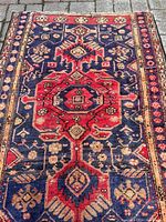 Full view of rug laid flat on stone ground showing central medallion and upper field