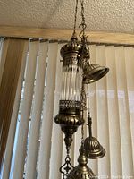 Photo shows one vintage Demmex Turkish Moroccan Ottoman era style hanging brass and Pyrex glass pendant light with detailed brass elements and ribbed cylindrical Pyrex glass.