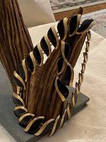 Choker necklace displayed on wood stand showing black enamel and gold metal leaf curved links