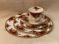 Full set arranged with teacup on saucer, stacked on plates showing floral pattern gold trim