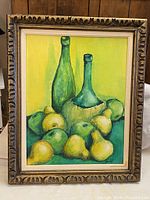 Frontal view of the framed still life painting with two green bottles and pears and apples on a yellow background, signed in lower right corner.