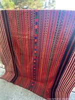 Front view of colorful vintage hand woven Moroccan style couch throw draped showing detailed striped and geometric patterned fabric.