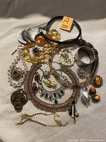 Full lot view showing various pieces including cuff bracelet, clip earrings, necklaces, brooches, and bracelets arranged on white cloth.
